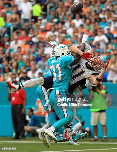 Julian Edelman of the New England Patriots has a pass blocked by Michael Thomas of the Miami Dolphins during a game at Hard Rock Stadium on January...