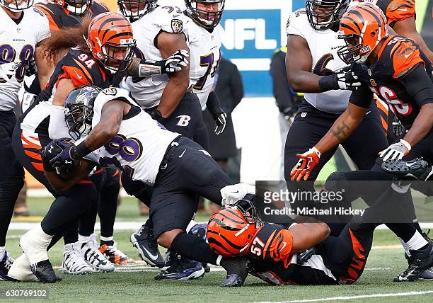 Vincent Rey of the Cincinnati Bengals wraps up the legs of Terrance West of the Baltimore Ravens as Domata Peko of the Cincinnati Bengals comes to...