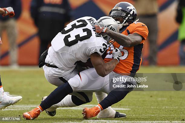 Darian Stewart of the Denver Broncos tackles DeAndre Washington of the Oakland Raiders during the first quarter on Sunday, January 1, 2017. The...