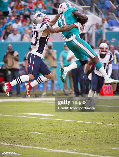 Miami Dolphins Wide Receiver DeVante Parker leaps up in the air to catches the ball in front of New England Patriots Safety Patrick Chung during the...