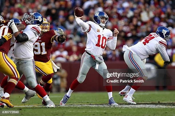 Quarterback Eli Manning of the New York Giants passes the ball while under pressure from outside linebacker Ryan Kerrigan of the Washington Redskins...