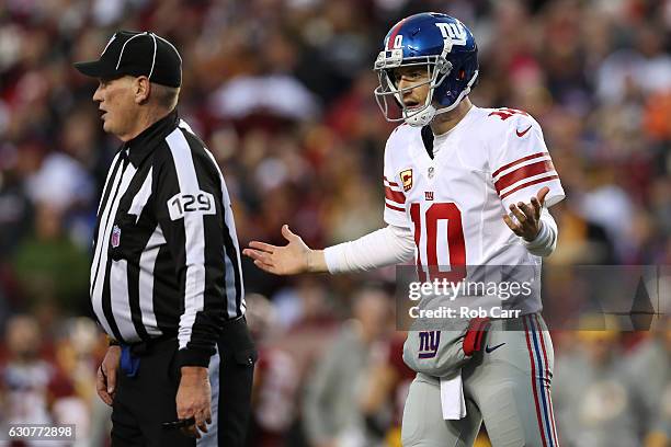 Quarterback Eli Manning of the New York Giants reacts while umpire Bill Schuster looks on in the first quarter of a game against the Washington...