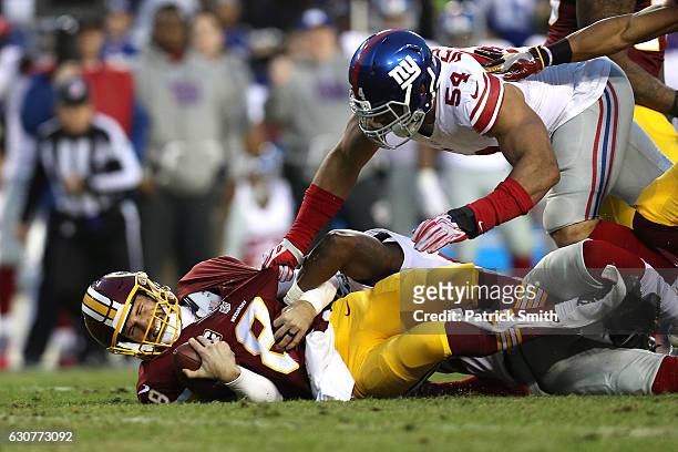 Quarterback Kirk Cousins of the Washington Redskins is sacked by defensive end Olivier Vernon and strong safety Landon Collins of the New York Giants...
