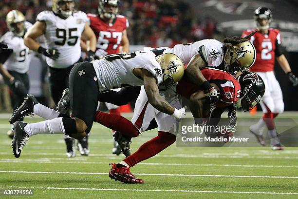 Vonn Bell and B.W. Webb of the New Orleans Saints tackle Julio Jones of the Atlanta Falcons during the second half at the Georgia Dome on January 1,...