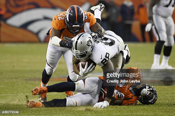 Corey Nelson of the Denver Broncos and Darian Stewart tackle Clive Walford of the Oakland Raiders during the third quarter on Sunday, January 1,...