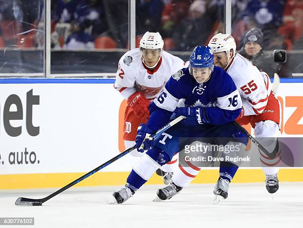 Mitchell Marner of the Toronto Maple Leafs stickhandles the puck with Andreas Athanasiou and Niklas Kronwall of the Detroit Red Wings chasing during...