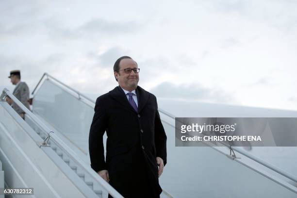 French President Francois Hollande walks down the gangway as he leaves his plane after his arrival at the airport in Baghdad on January 2, 2017....