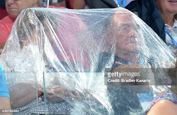 Fans are seen trying to protect themselves from the rain as the match between Steve Johnson of the USA and Grigor Dimitrov of Bulgaria is suspended...