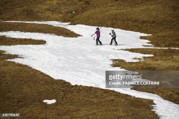 Skiers walk in a snowless landscape on January 2, 2017 in the Swiss Alps resort of les Crosets. Switzerland has just experienced its driest December...