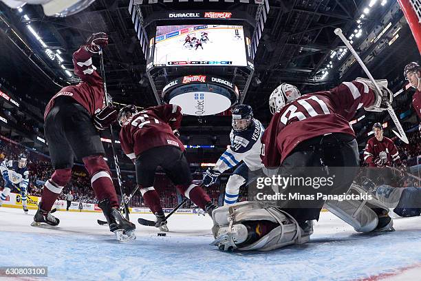 Kristian Vesalainen of Team Finland tries to get a shot on goaltender Mareks Mitens of Team Latvia during the 2017 IIHF World Junior Championship...