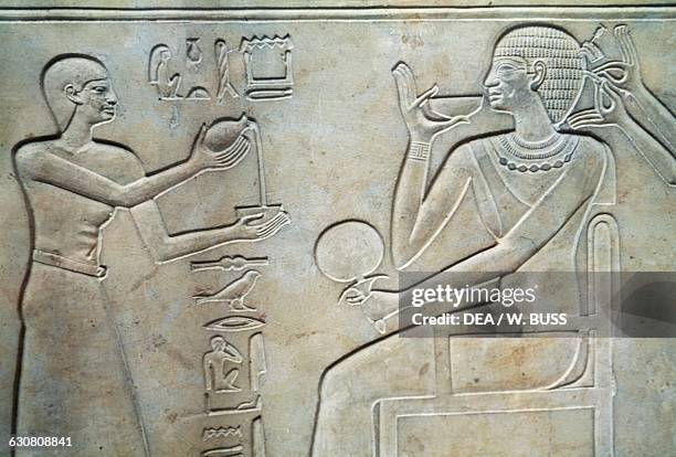 Seated deceased being assisted by a male and female servant, bas-relief on the sarcophagus of Princess Kawit, 2050 BC, from the Temple of Mentuhotep...