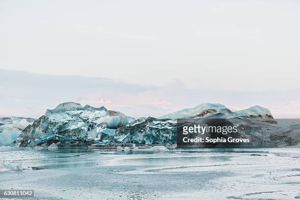 An overturned iceberg glistens bright blue in Jokulsarlon glacier lagoon on January 2, 2017 in Reykjavik, Iceland.