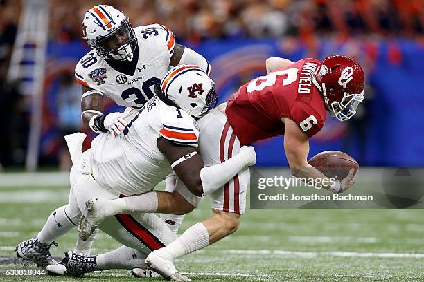 Baker Mayfield of the Oklahoma Sooners is tackled by Montravius Adams of the Auburn Tigers during the Allstate Sugar Bowl at the Mercedes-Benz...