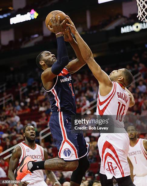 John Wall of the Washington Wizards has his shot blocked by Eric Gordon of the Houston Rockets as he drives to the basket in the second half at...