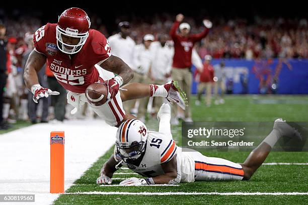 Joe Mixon of the Oklahoma Sooners scores a touchdown over Joshua Holsey of the Auburn Tigers during the Allstate Sugar Bowl at the Mercedes-Benz...