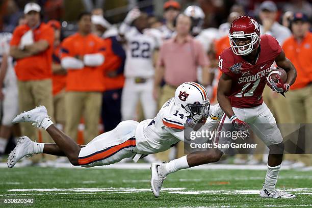 Dede Westbrook of the Oklahoma Sooners is tackled by Stephen Roberts of the Auburn Tigers during the Allstate Sugar Bowl at the Mercedes-Benz...