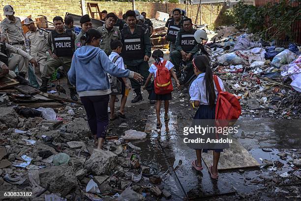 Mother walks her children to school as polices gather during a protest at the Borei Keila site in Phnom Penh, Cambodia on January 3, 2017. Families...