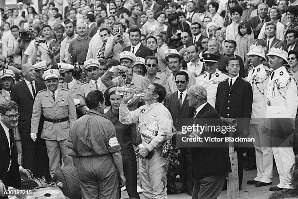 Scottish racing driver Jackie Stewart having a drink after winning the Monaco Grand Prix in a BRM P261, Monte Carlo, 22nd May 1966. On his right is...