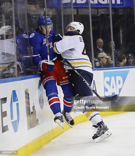 Brady Skjei of the New York Rangers is checked into the boards by Nicolas Deslauriers of the Buffalo Sabres during the third period at Madison Square...