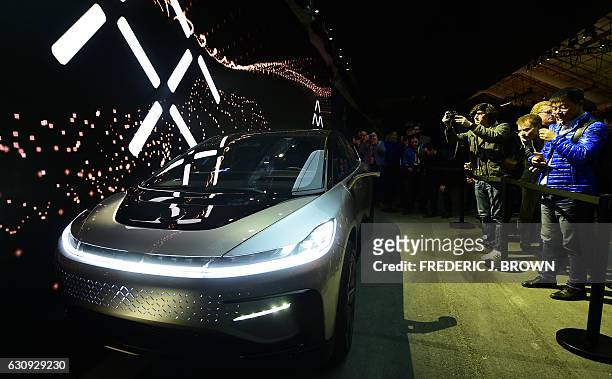 People crowd up to the barricade to capture images of the FF91 electric vehicle from Faraday Future at the company's press conference at the 2017...