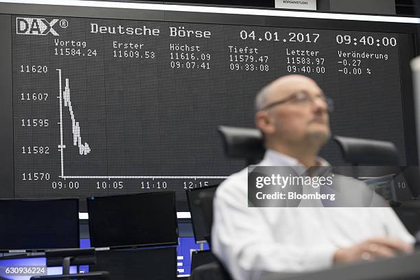 Trader monitors financial data as the DAX Index curve is displayed inside the Frankfurt Stock Exchange in Frankfurt, Germany, on Wednesday, Jan. 4,...