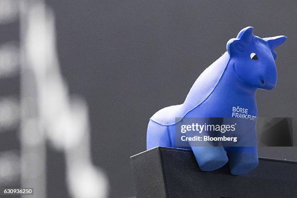 Bull figurine sits on a trader's monitor as the DAX Index curve is displayed beyond inside the Frankfurt Stock Exchange in Frankfurt, Germany, on...