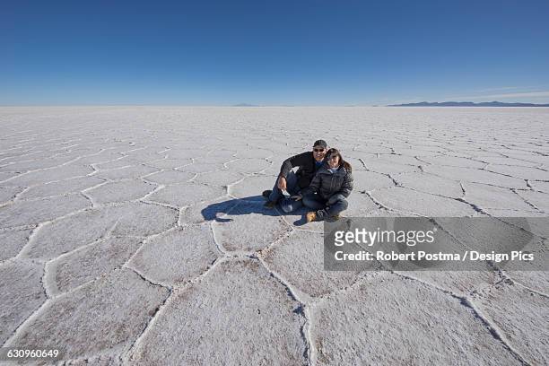couple sitting on the salt flats of the salar de uyuni - bolivia daily life stock pictures, royalty-free photos & images