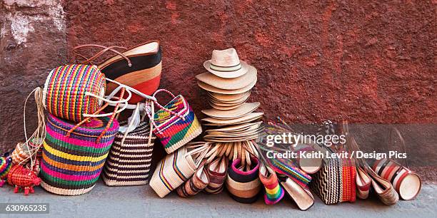 woven souvenirs on display on a sidewalk against a wall - san miguel de allende fotografías e imágenes de stock