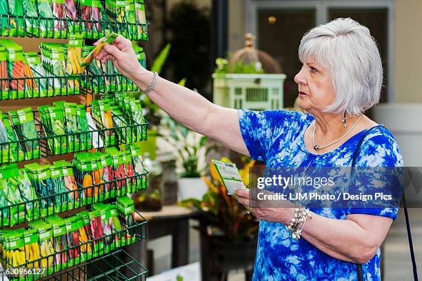 mature woman shopping for garden seeds in a garden centre in a shopping complex - same person different outfits stock-fotos und bilder