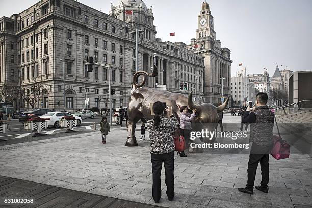 Woman poses for photographs with the Bund Bull in Shanghai, China, on Wednesday, Jan. 4, 2017. After defying skeptics with solid growth last year,...