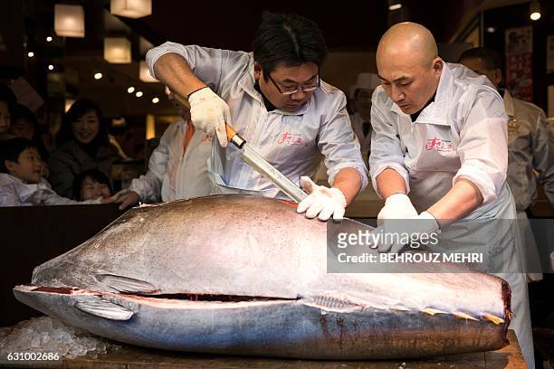 Employees of sushi restaurant chain Sushi-Zanmai cut a 212-kilogram bluefin tuna at their restaurant near the Tsukiji fish market in Tokyo on January...