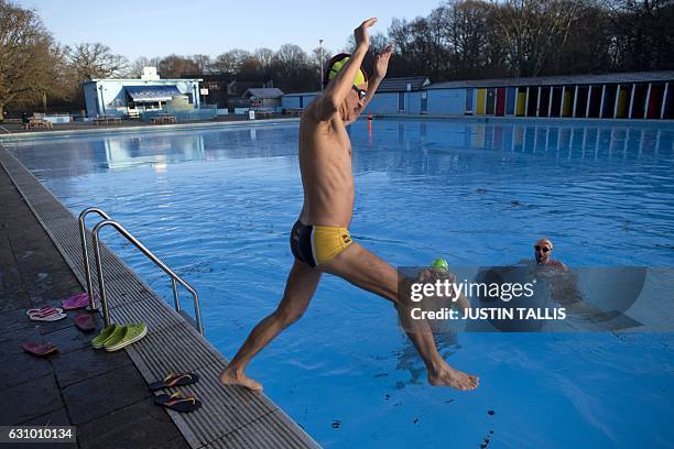 Swimmer jumps into the ice cold water at Tooting Bec Lido, in south west London on January 5 at sunrise on a freezing winter morning. / AFP / Justin...