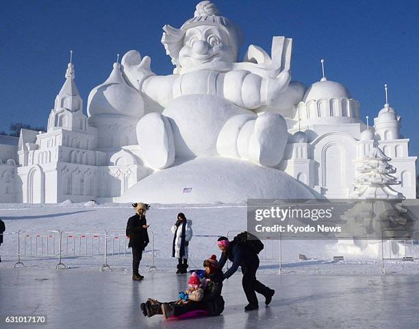 Man pushes a sled carrying a child in front of a large snow structure in Harbin, the capital of China's northeastern Heilongjiang Province, on Jan. 5...