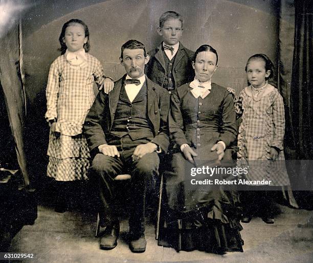 Family poses in a photography studio, circa 1860, for a tintype portrait, also known as a ferrotype, a popular photographic format which first...