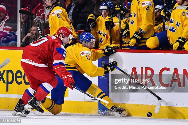 Filip Ahl of Team Sweden and Alexander Polunin of Team Russia chase after the puck near the boards during the 2017 IIHF World Junior Championship...