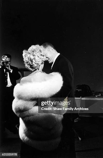 Marilyn Monroe, wearing a white fur stole wrap, with director Billy Wilder on set for a publicity photo shoot with Richard Avedon in his studio...