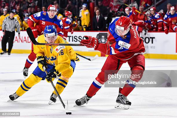 Carl Grundstrom of Team Sweden tries to poke the puck away from Kirill Urakov of Team Russia during the 2017 IIHF World Junior Championship bronze...