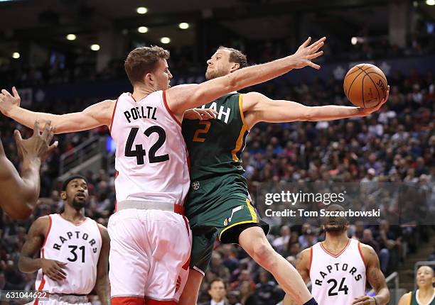 Joe Ingles of the Utah Jazz passes the ball under the basket as Jakob Poeltl of the Toronto Raptors guards him during NBA game action at Air Canada...