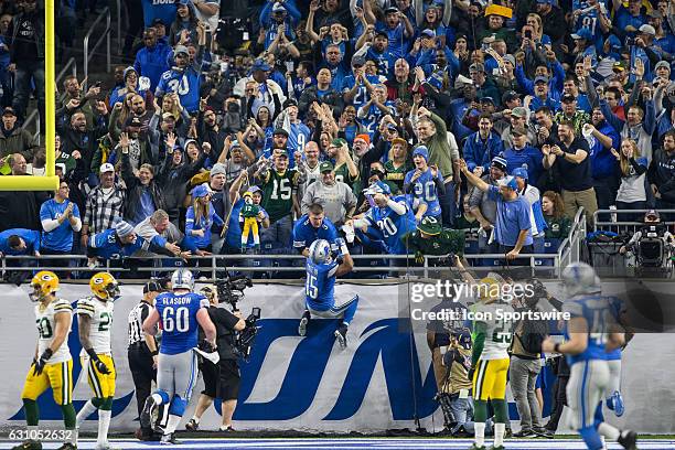 Detroit Lions wide receiver Golden Tate climbs the wall at the back of the end zone to celebrate with fans after scoring a touchdown during game...