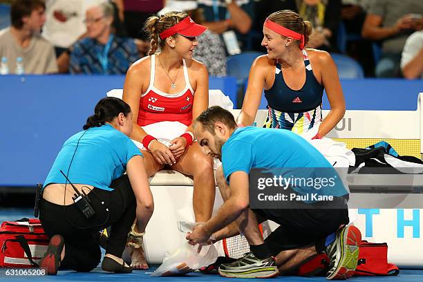 Belinda Bencic of Switzerland and Kristina Mladenovic of France share a moment on the Swiss bench as trainers attend to an injured toe in the women's...