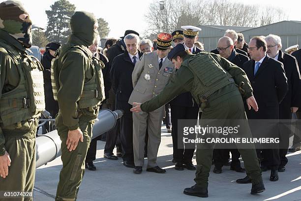Serviceman shows military equipments to French President Francois Hollande , flanked by French Defence Minister Jean-Yves Le Drian , French Junior...