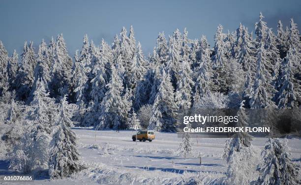 Car drives past frost covering the trees and fields in Belmont, eastern France on January 6, 2017.