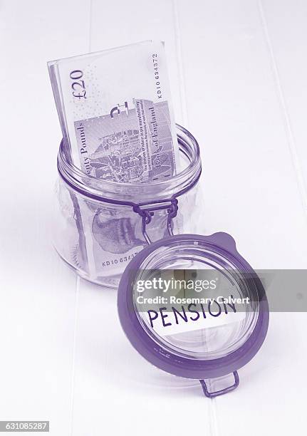 jar & twenty pound notes in monochromatic purple - saving for a rainy day englische redewendung stock-fotos und bilder