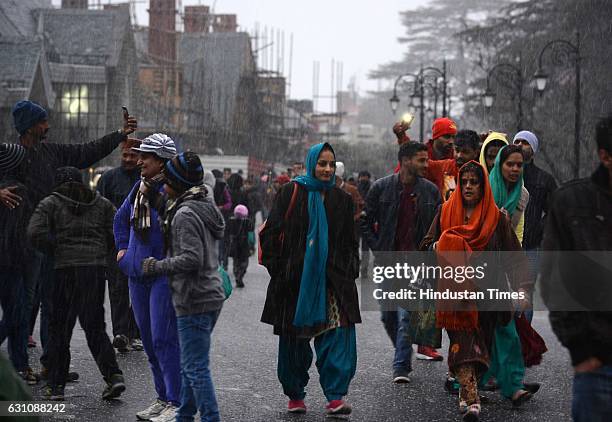 People enjoy walking in the light rain and sleet in the evening at Ridge, on January 6, 2017 in Shimla, India.