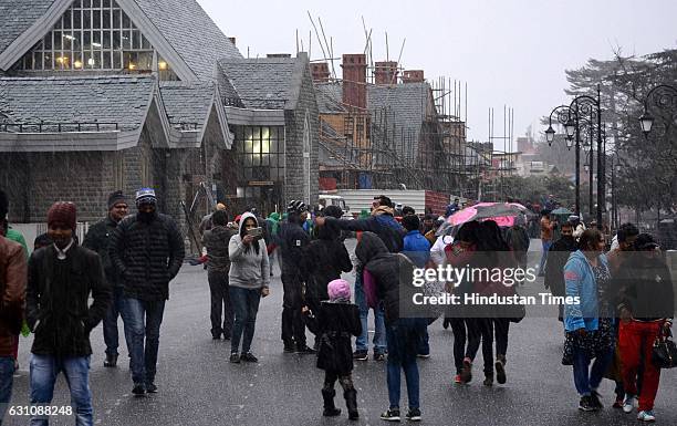 People enjoy walking in the light rain and sleet in the evening at Ridge, on January 6, 2017 in Shimla, India.