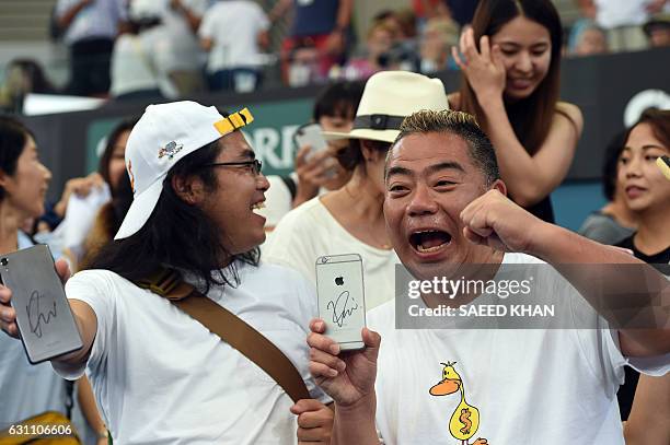 This photo taken on January 6, 2017 shows Japanese comedians Roch Nakaokal and Tetsuro Degawa displaying their autographed mobile phone signed by...