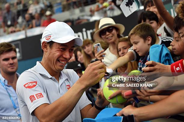 This photo taken on January 6, 2017 shows Japan's Nei Nishikori laughing on a joke cracked by Japanese comedian Tetsuro Degawa after his victory over...