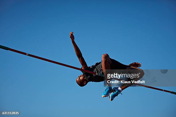 male athlete doing high jump at sunset - leichtathletik stock-fotos und bilder