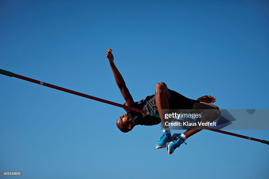 Male athlete doing high jump at sunset