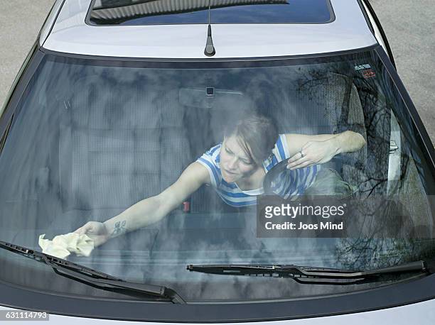 woman cleaning car window - windscreen stockfoto's en -beelden